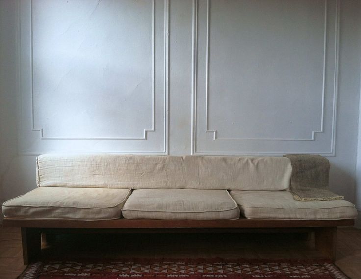 a white couch sitting on top of a wooden floor next to a red and white rug