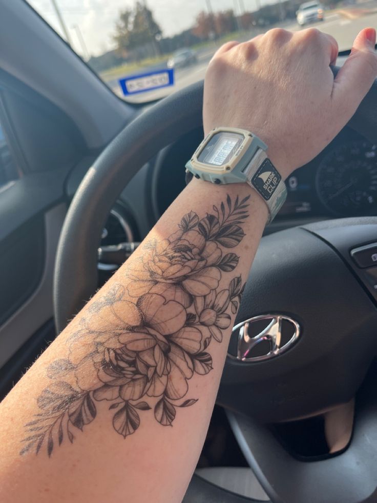 a woman's arm with flowers on it and a watch in the middle of her arm