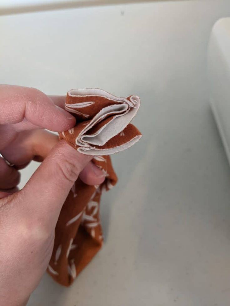 a person holding a piece of food with icing on it in front of a sink