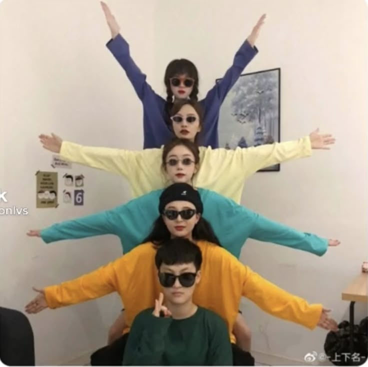 five people with their arms in the air and one person wearing sunglasses on top of them