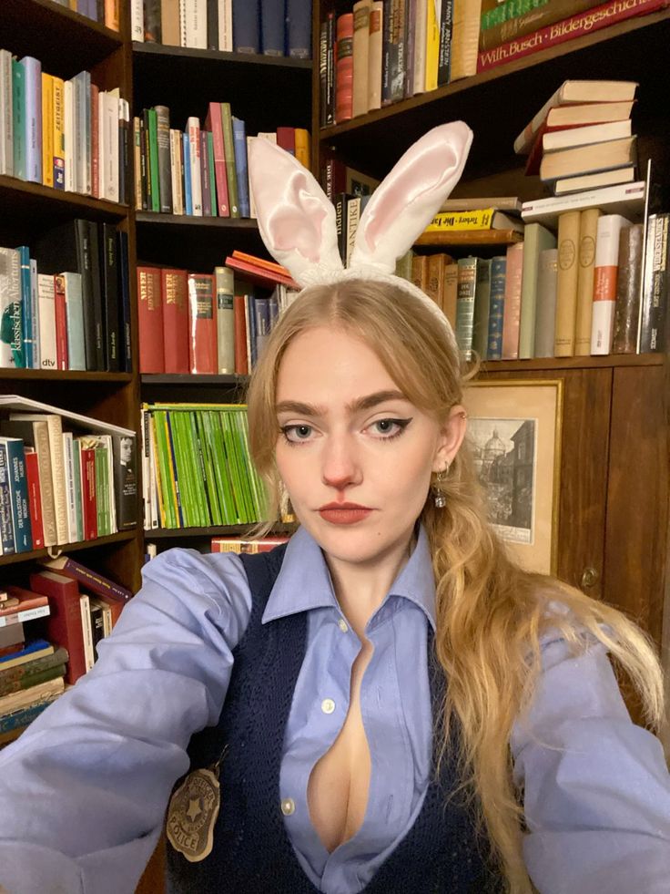 a woman sitting in front of a bookshelf with bunny ears on her head