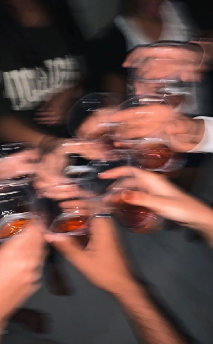 many people are holding their glasses in the shape of a circle and reaching for each other