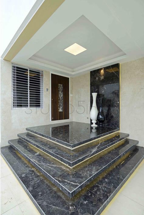 three black and white vases sitting on top of marble steps in front of a door