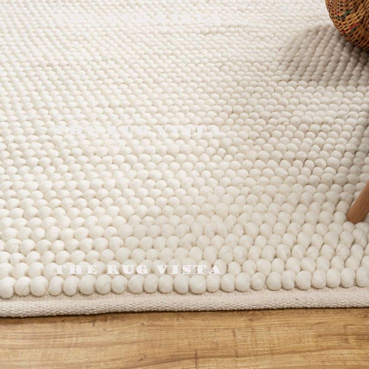 a close up of a white rug on a wooden floor with a basket next to it