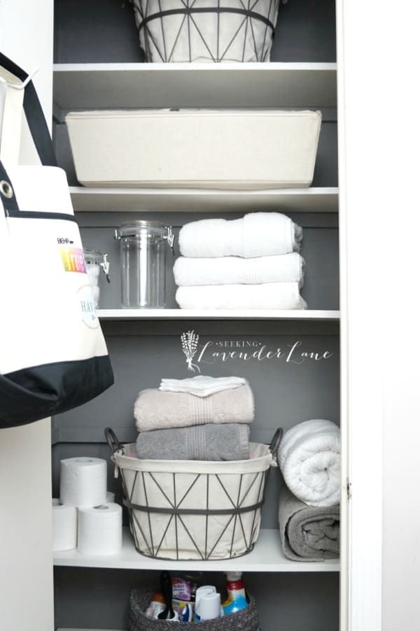 an organized closet with baskets and towels