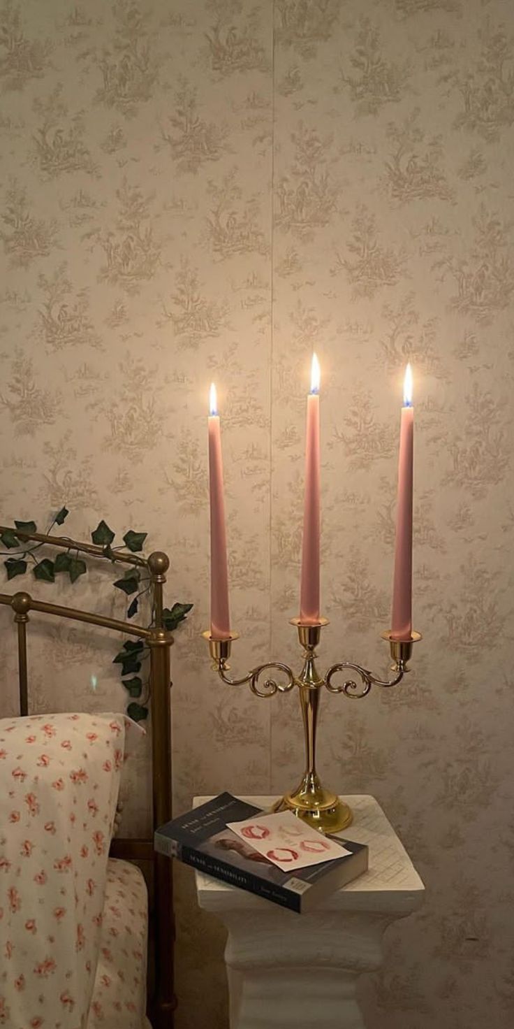 three candles are lit on top of a small table in front of a wallpapered room