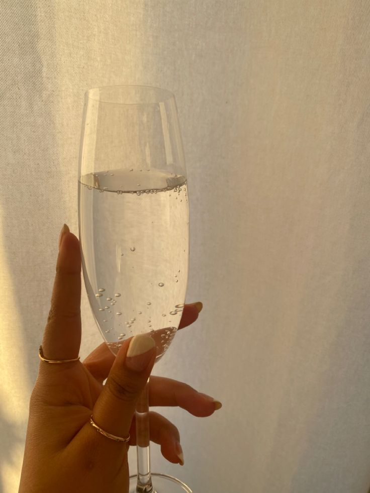 a hand holding a wine glass with water in it