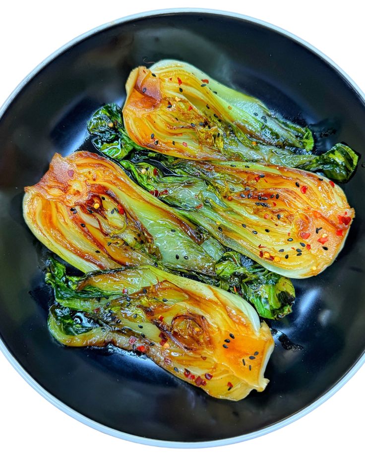 cooked vegetables in a black bowl on a white table