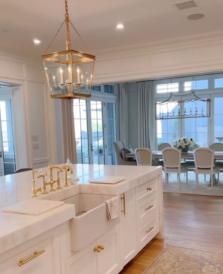 a large kitchen with white cabinets and gold accents on the countertop, along with a chandelier