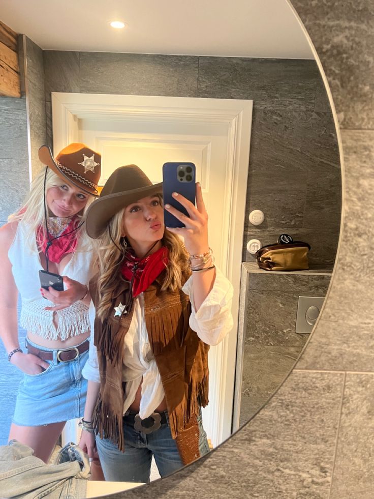 a woman taking a selfie in front of a mirror with a cowboy hat on