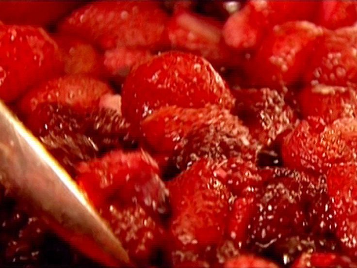 strawberries being cooked in a pot with a spoon