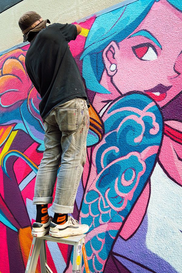 a man is painting a mural on the side of a building