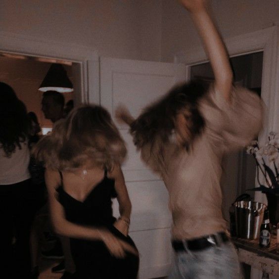 two people dancing in a room with other people