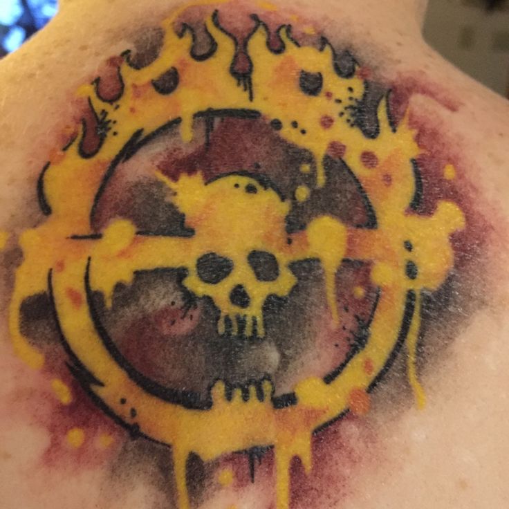 the back of a man's chest with yellow ink on it and a skull in the center