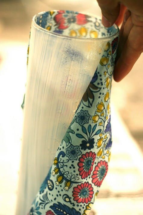 a person is holding a white vase with colorful flowers on it and the bottom half has a flowered design