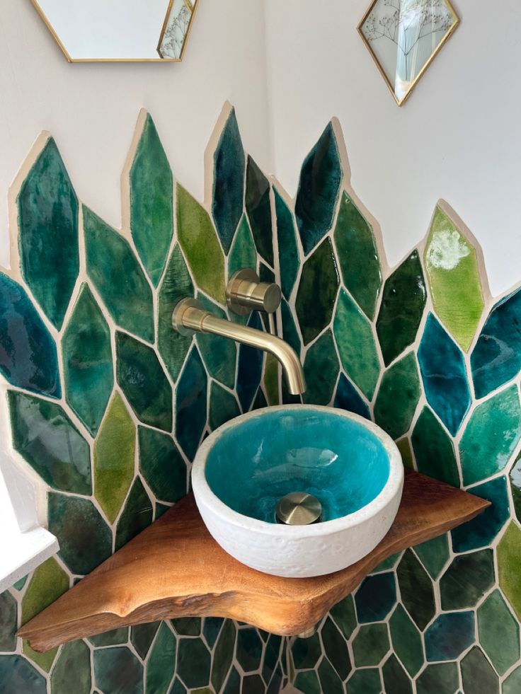 a bathroom sink with green and blue tiles on the wall