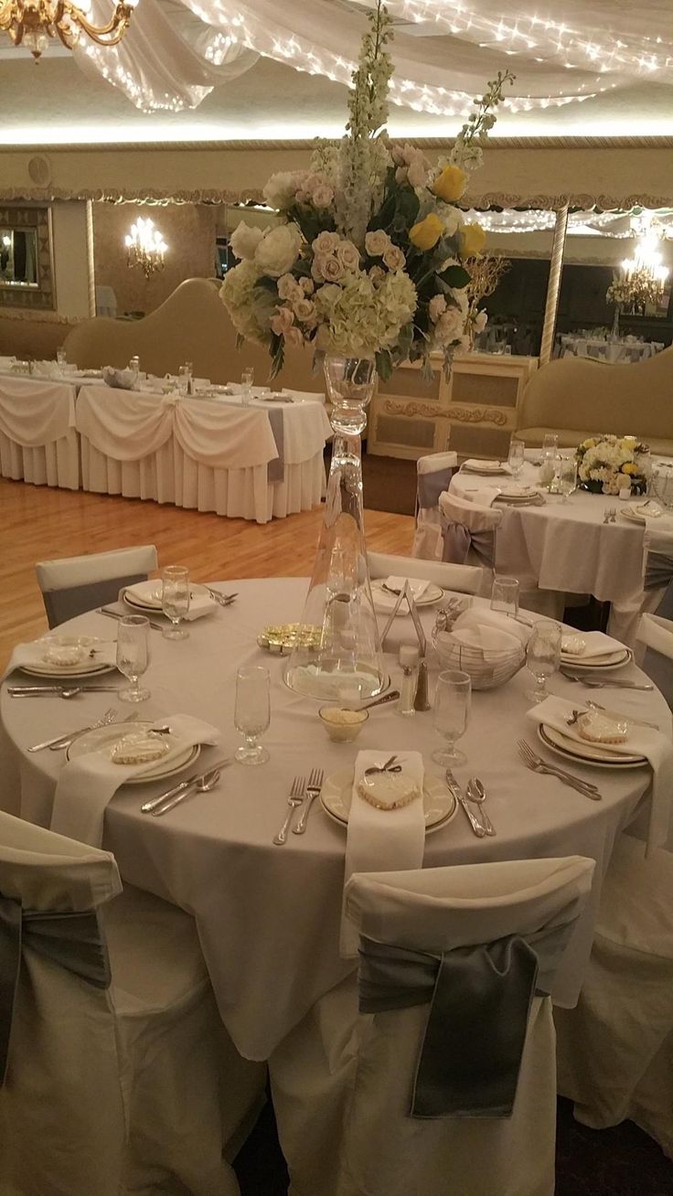 a banquet room with white linens and tables set for formal dinner or wedding reception