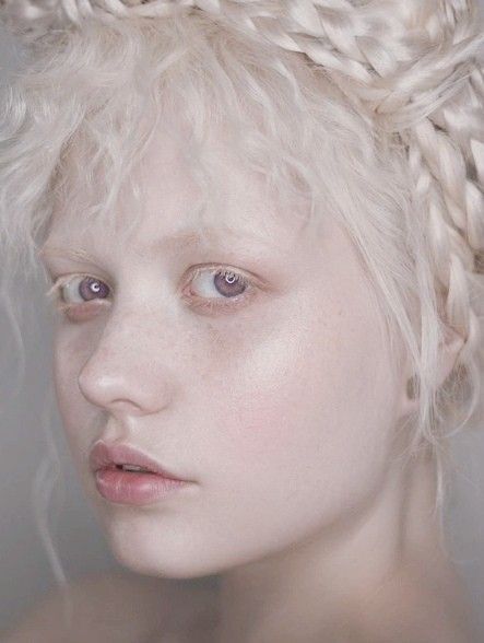 a woman with white hair and braids on her head is looking at the camera