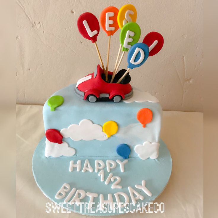 a birthday cake decorated with balloons and a car