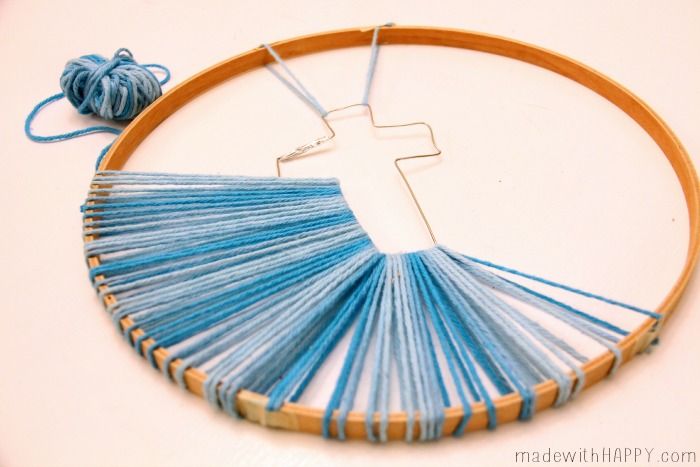 a cross on a wooden hoop with blue thread