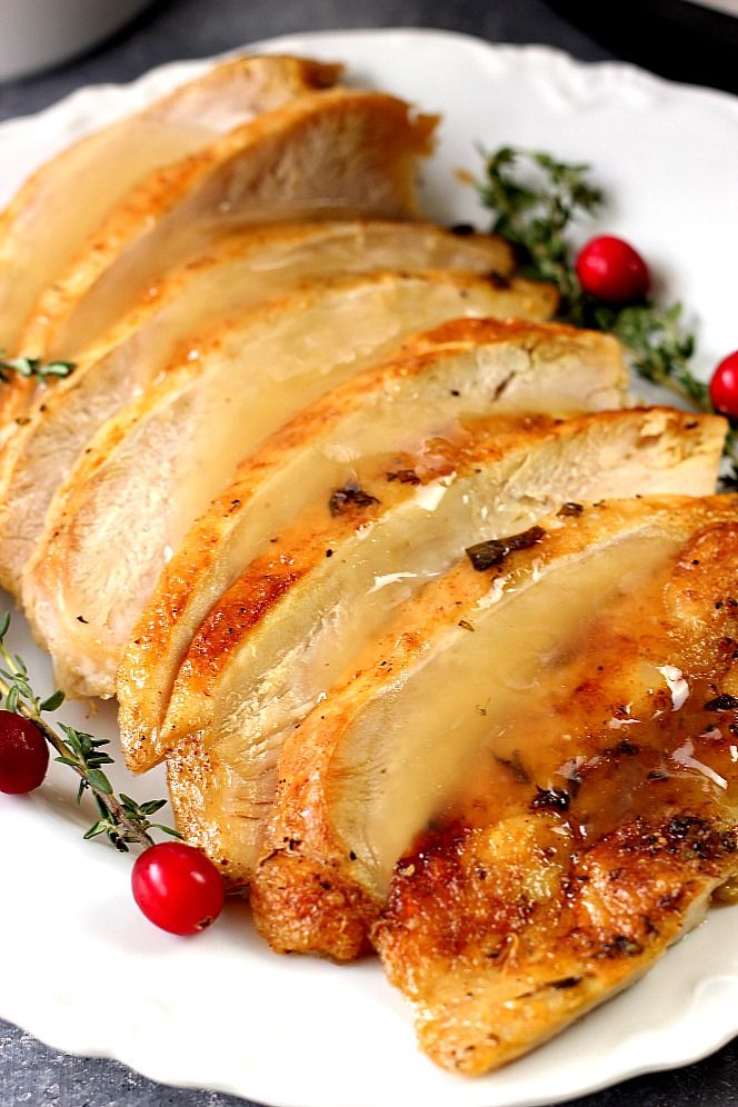 slices of chicken on a plate with cranberries and herbs