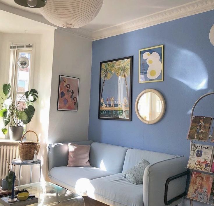 a living room with blue walls and pictures hanging on the wall, including a couch