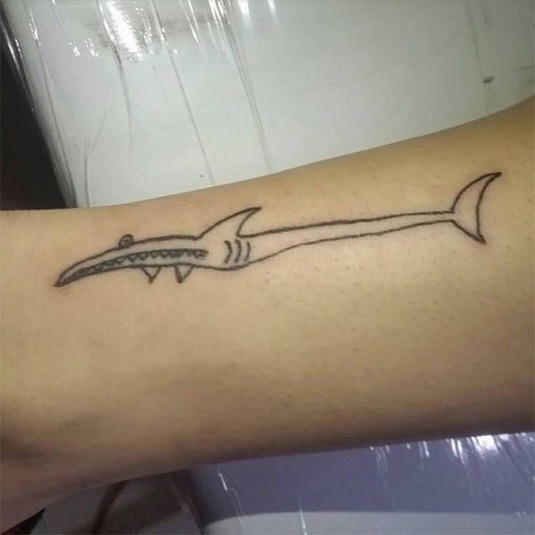 a tattoo on the arm of a person with a shark tail and sharp knife in it