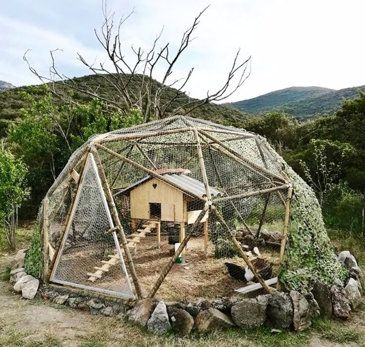 a chicken coop built into the side of a hill with rocks and trees around it