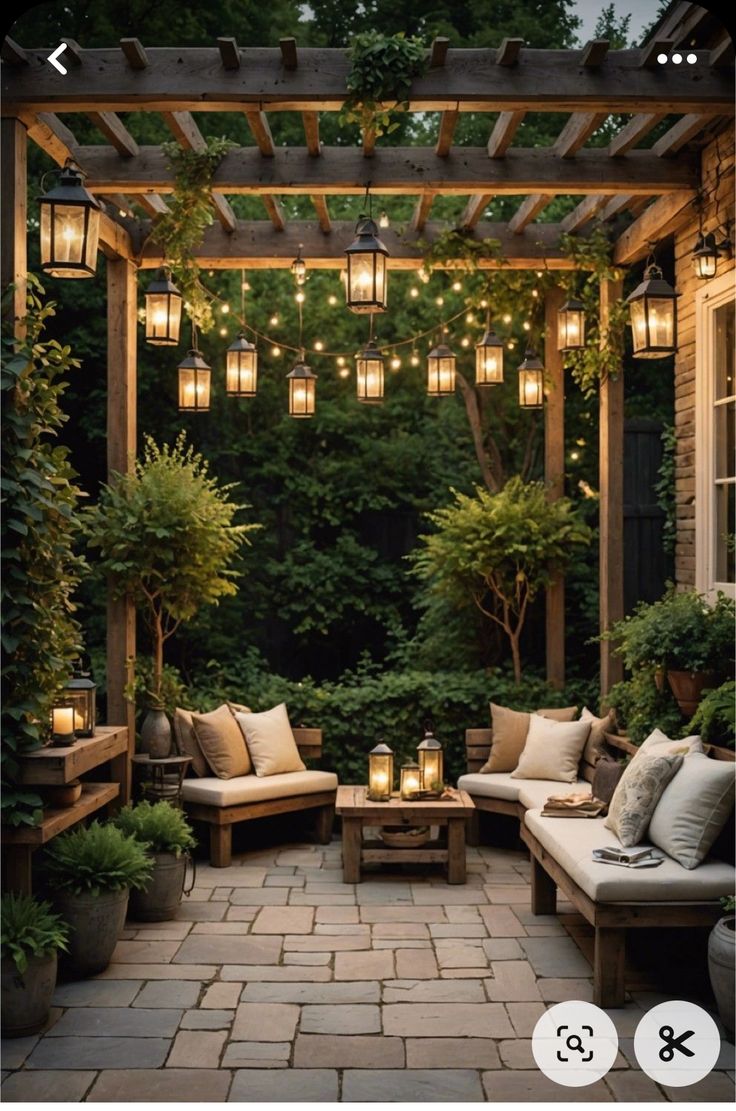 an outdoor seating area with lights strung from the ceiling and potted trees in the background