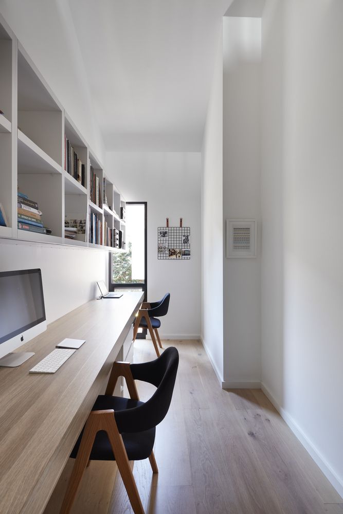 a long table with two chairs and a computer monitor on it in front of a bookshelf