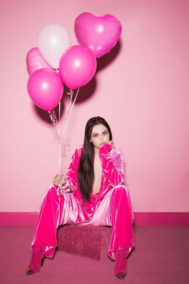 a woman in pink is sitting on a bench with balloons