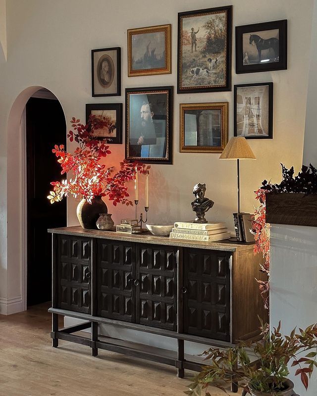 a living room with pictures on the wall and a table in front of some plants