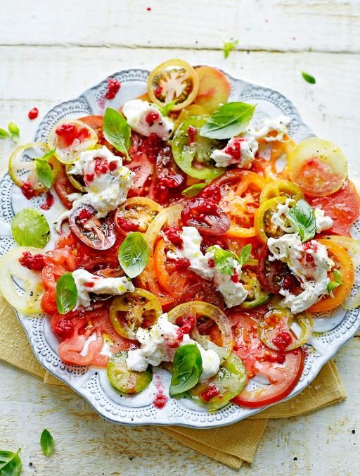 a white plate topped with sliced tomatoes and other veggies on top of a wooden table