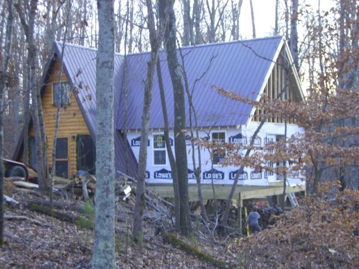 a house in the woods is being built with wood and metal shingles on it's roof