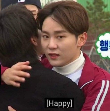 two young men hugging each other in front of a green sign that says happy on it