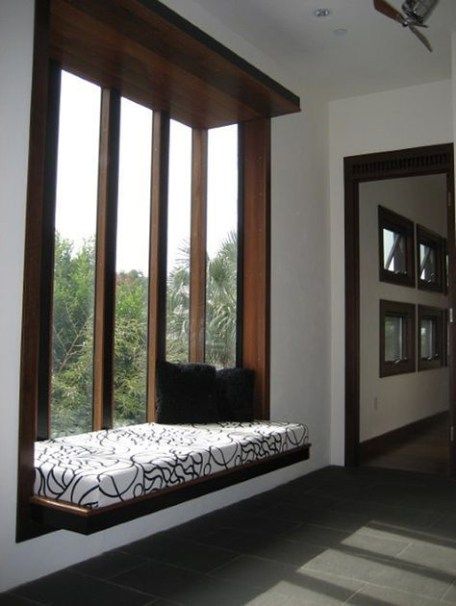 a window seat in the corner of a room with large windows and wood trimmings