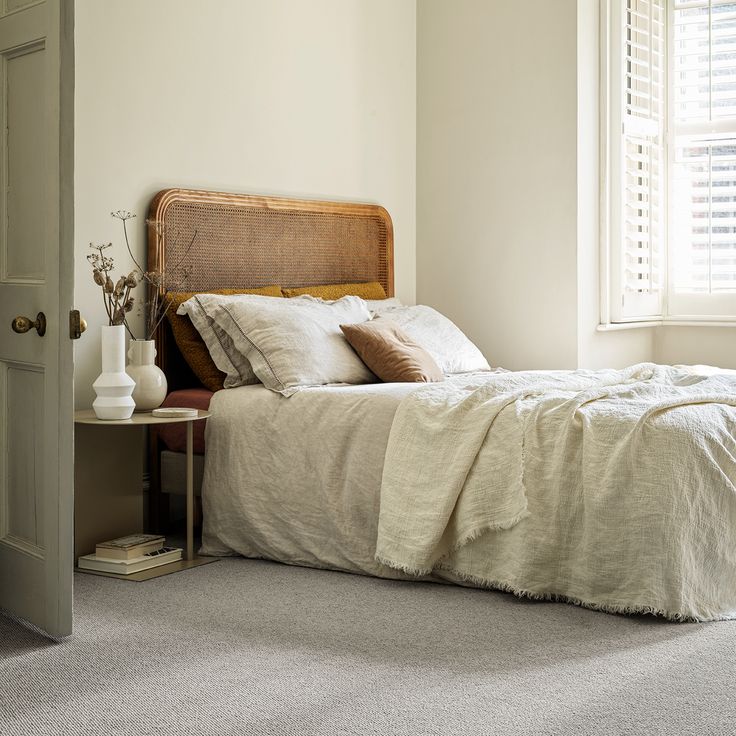 a bed sitting in a bedroom next to a window on top of a carpeted floor