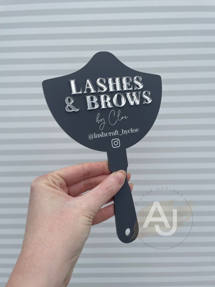 a person holding up a sign that says lashes and brows on the side of a wall