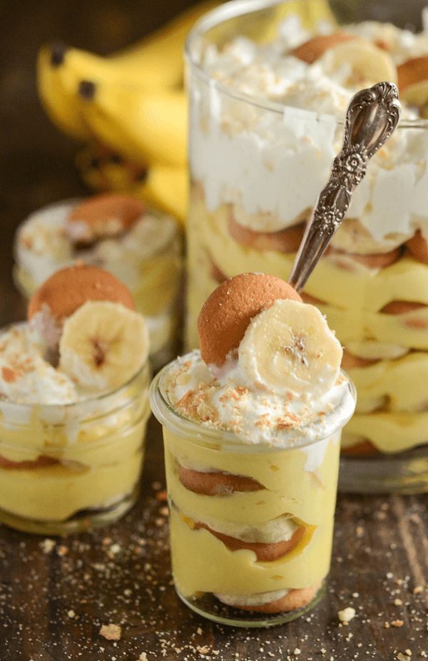 two desserts with bananas and whipped cream in them are sitting on a wooden table