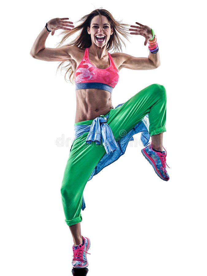 a woman is jumping in the air with her arms out and legs crossed, wearing green pants