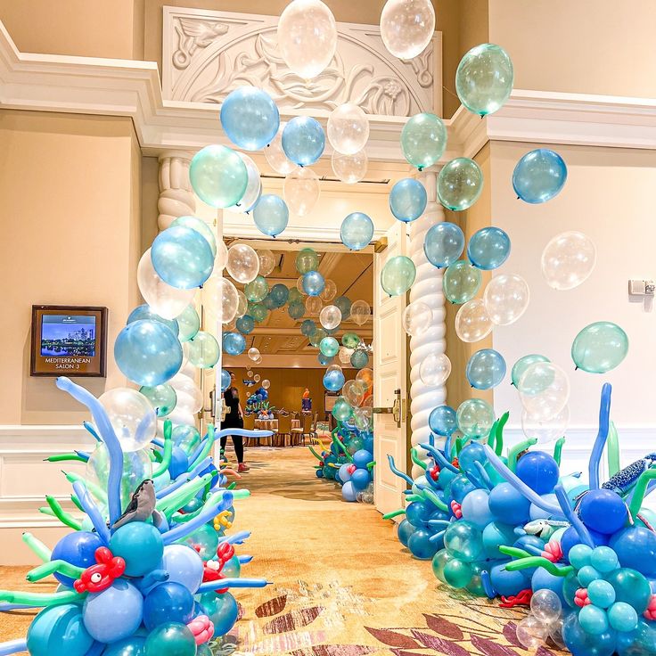 balloons are floating in the air near an archway decorated with corals and seaweed