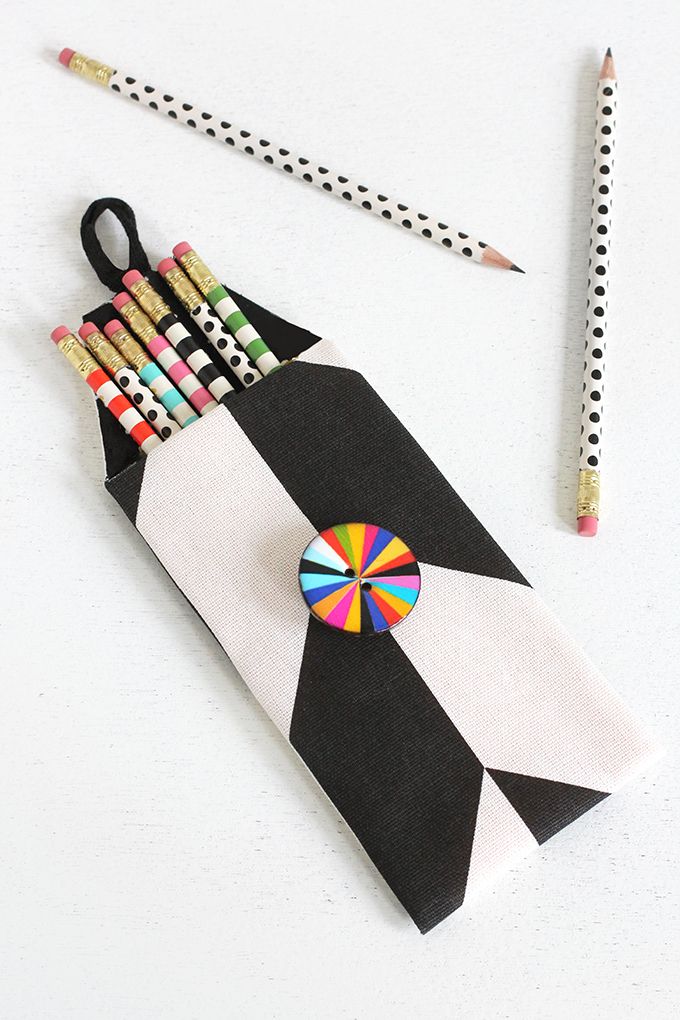 pencils and markers are placed in a black and white bag with an origami pinwheel on it