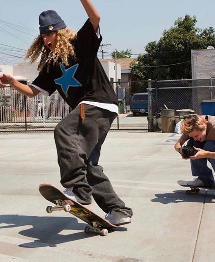 two skateboarders are doing tricks on their boards in the street while another person crouches down behind them