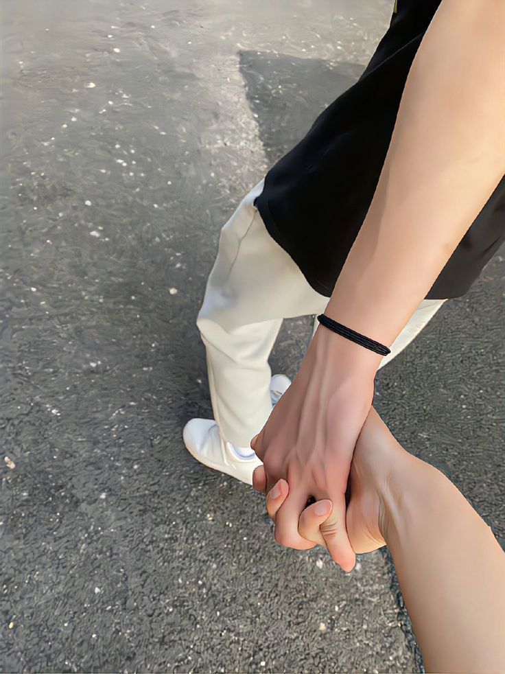 two people holding hands while walking down the street with their feet on each other's legs