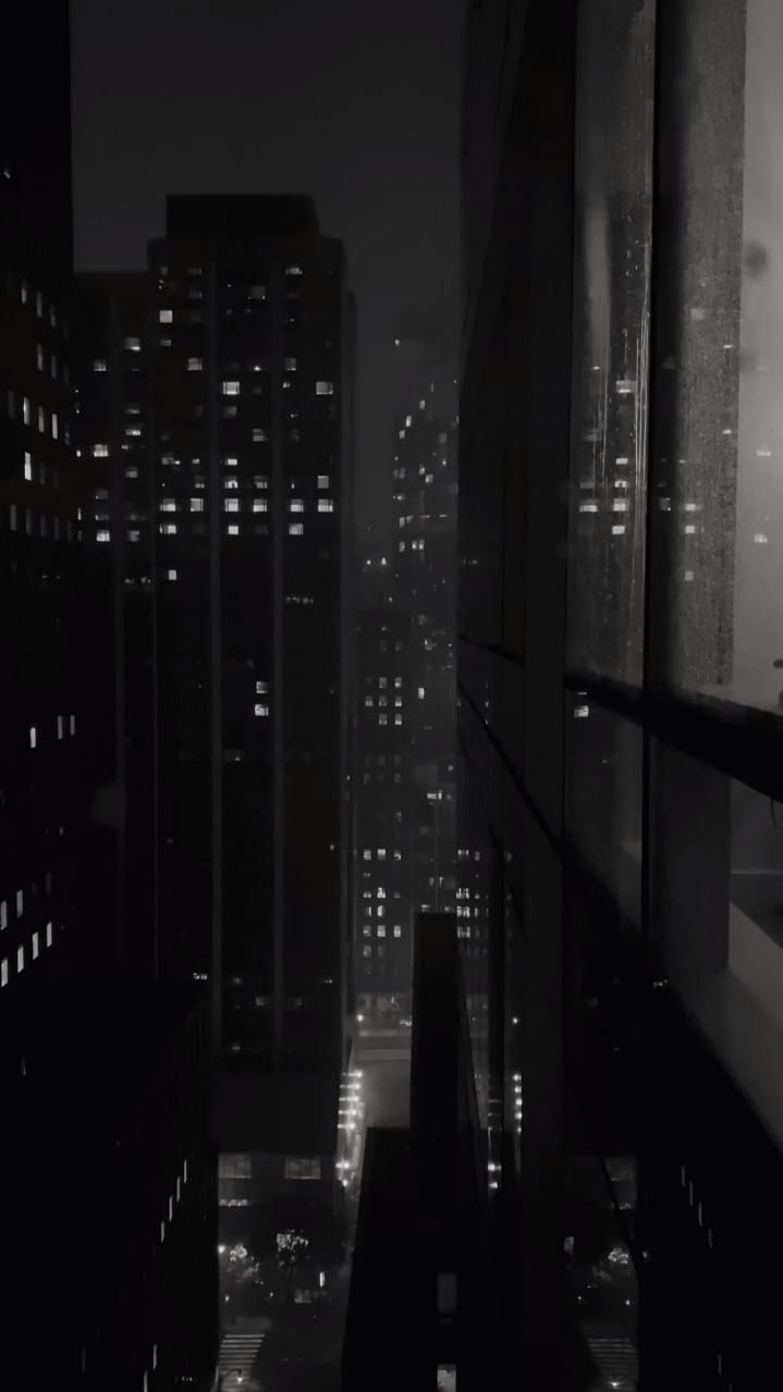 black and white photo of city at night with skyscrapers in the foreground, dark sky