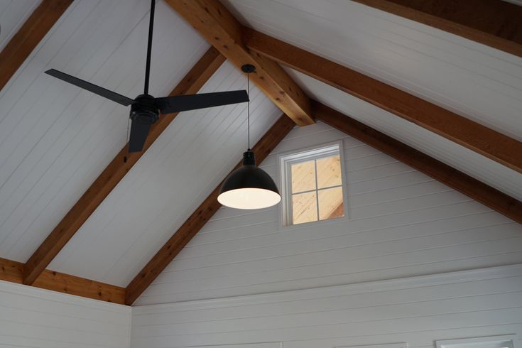 a ceiling fan is hanging from the ceiling in a room with white walls and wood beams