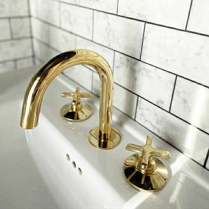 the faucet is gold in color on the white tile wall above the sink