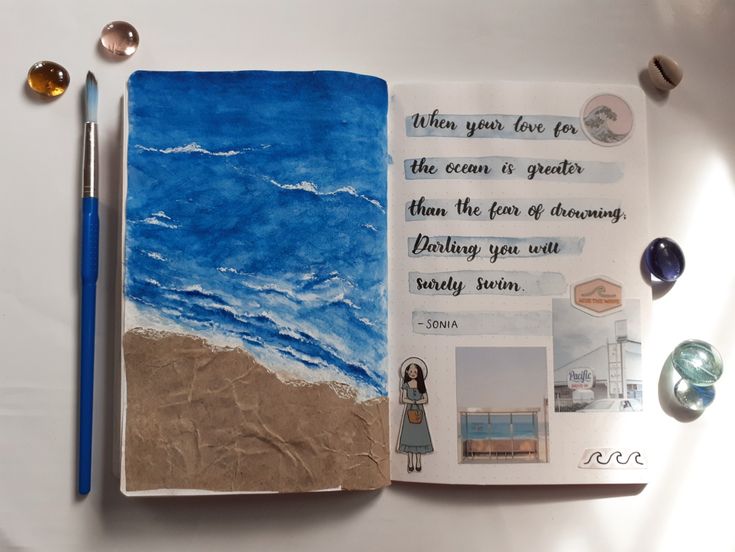 an open notebook with pictures and writing on the page next to a blue ballpoint pen