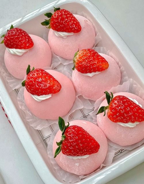 strawberry cheesecakes with whipped cream and fresh strawberries on top in a white tray