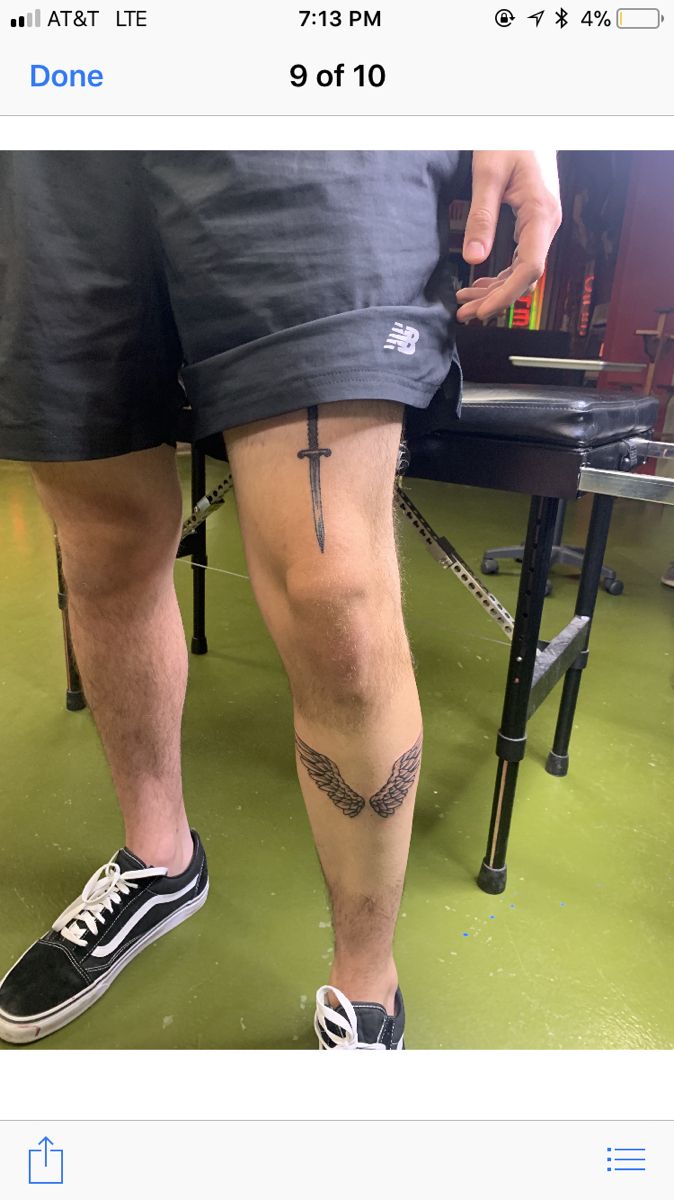 a man with tattoos on his legs standing next to a table